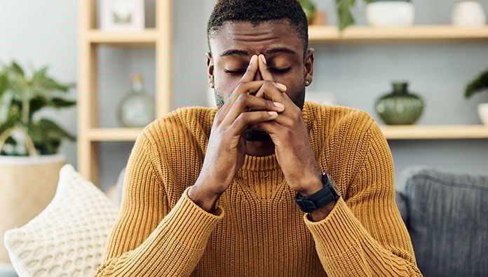 A man who looks stressed with his hands on his face A man who looks stressed with his hands on his face